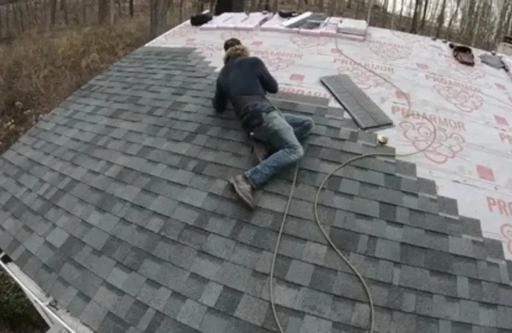 Person repairing shingles on a roof